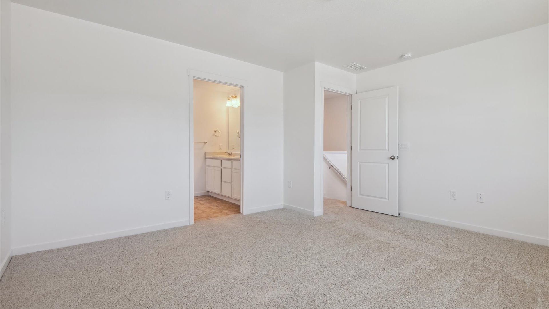 Alternate view of Douglas primary bedroom facing bedroom door and entryway into private bathroom, with stairwell beyond