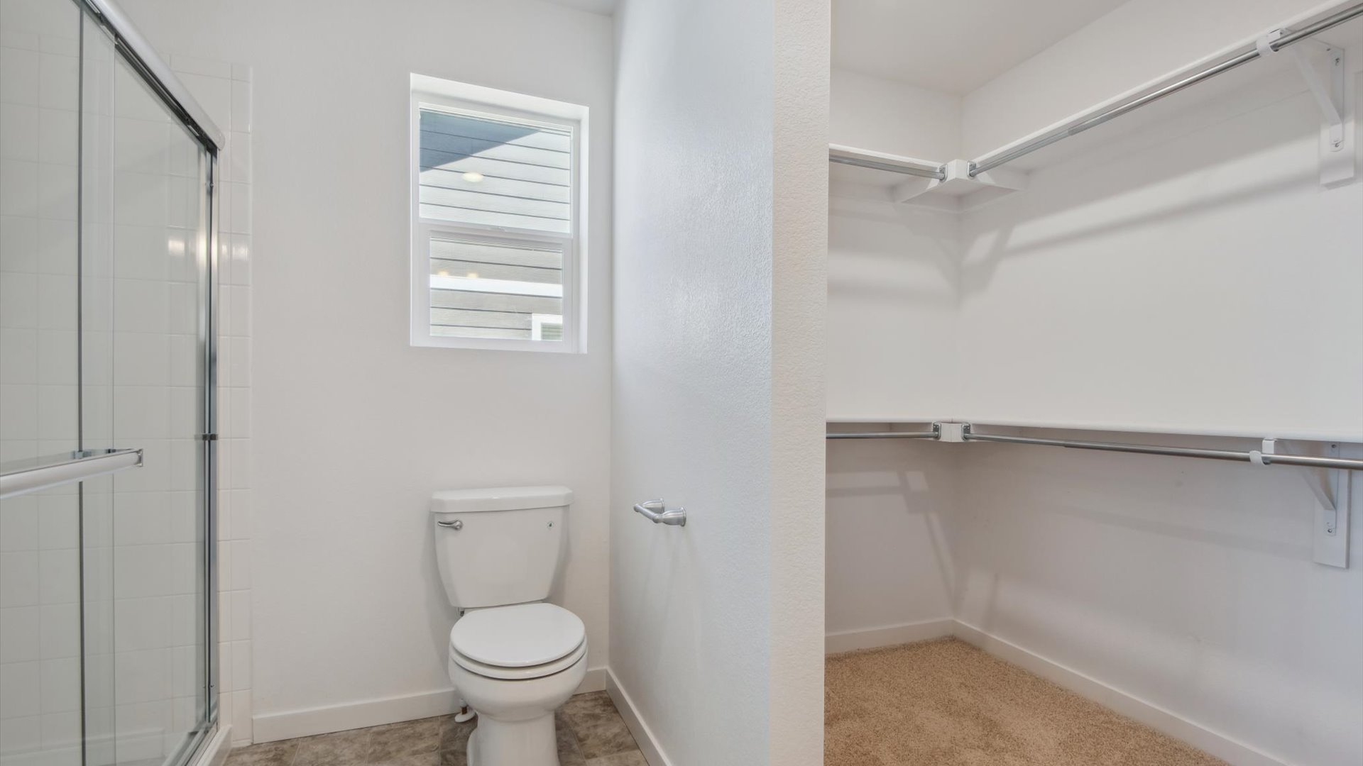 Private bathroom in Douglas plan with large walk-in closet, window above toilet and large glass-enclosed step-in shower