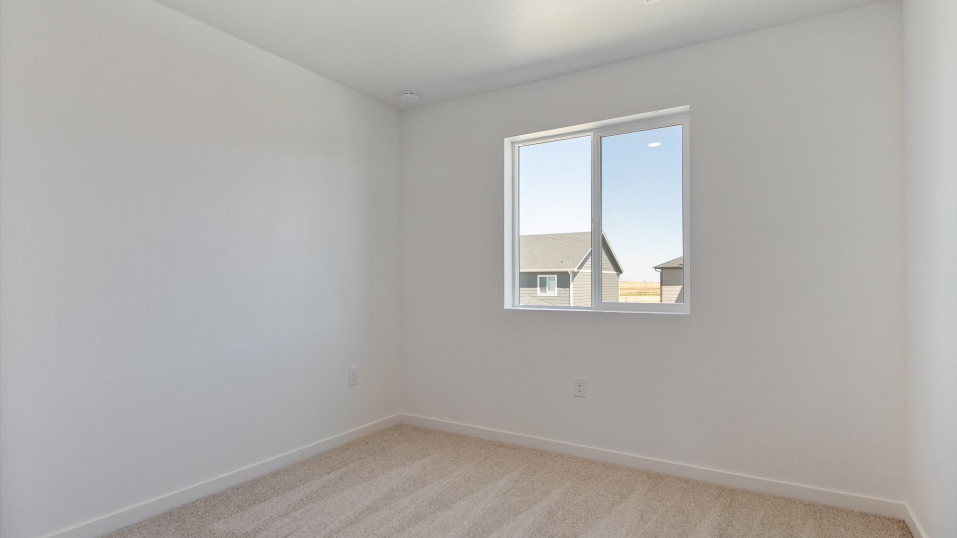 Douglas floor plan secondary bedroom with large operational window, multiple power outlets, white baseboard and plush carpet