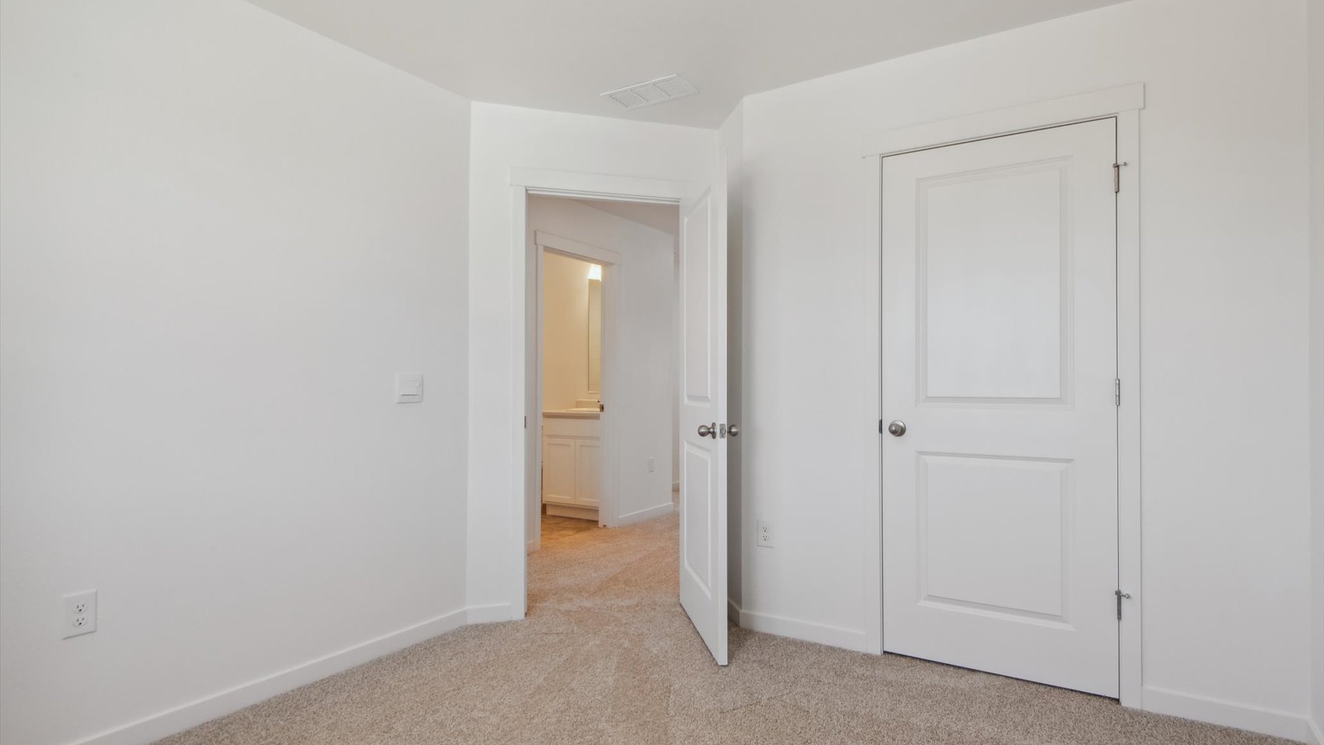 Another secondary bedroom in the Douglas home plan facing the bedroom door and storage closet, with view to the hallway bath