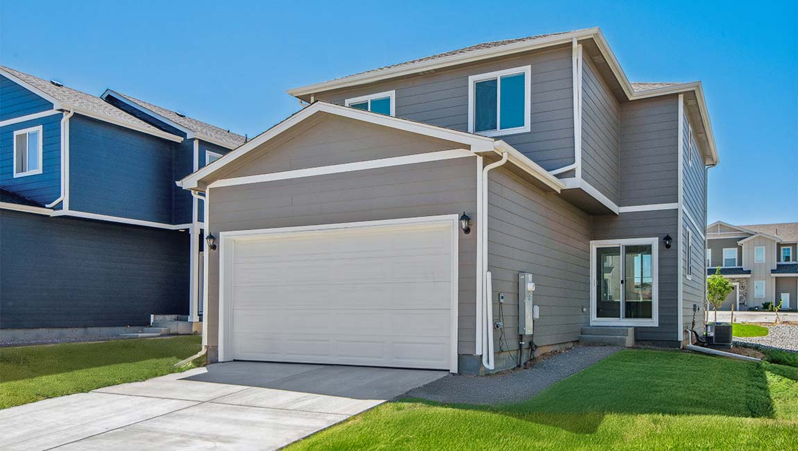 Douglas exterior displaying the rear of the home featuring 2-car garage door with sconce lighting and access door to dining