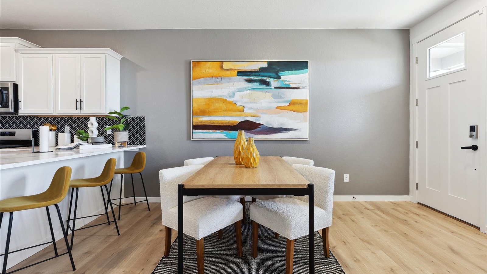Wide angle view of Larimer model dining room that shows multi-panel entry door with window and full height kitchen backsplash