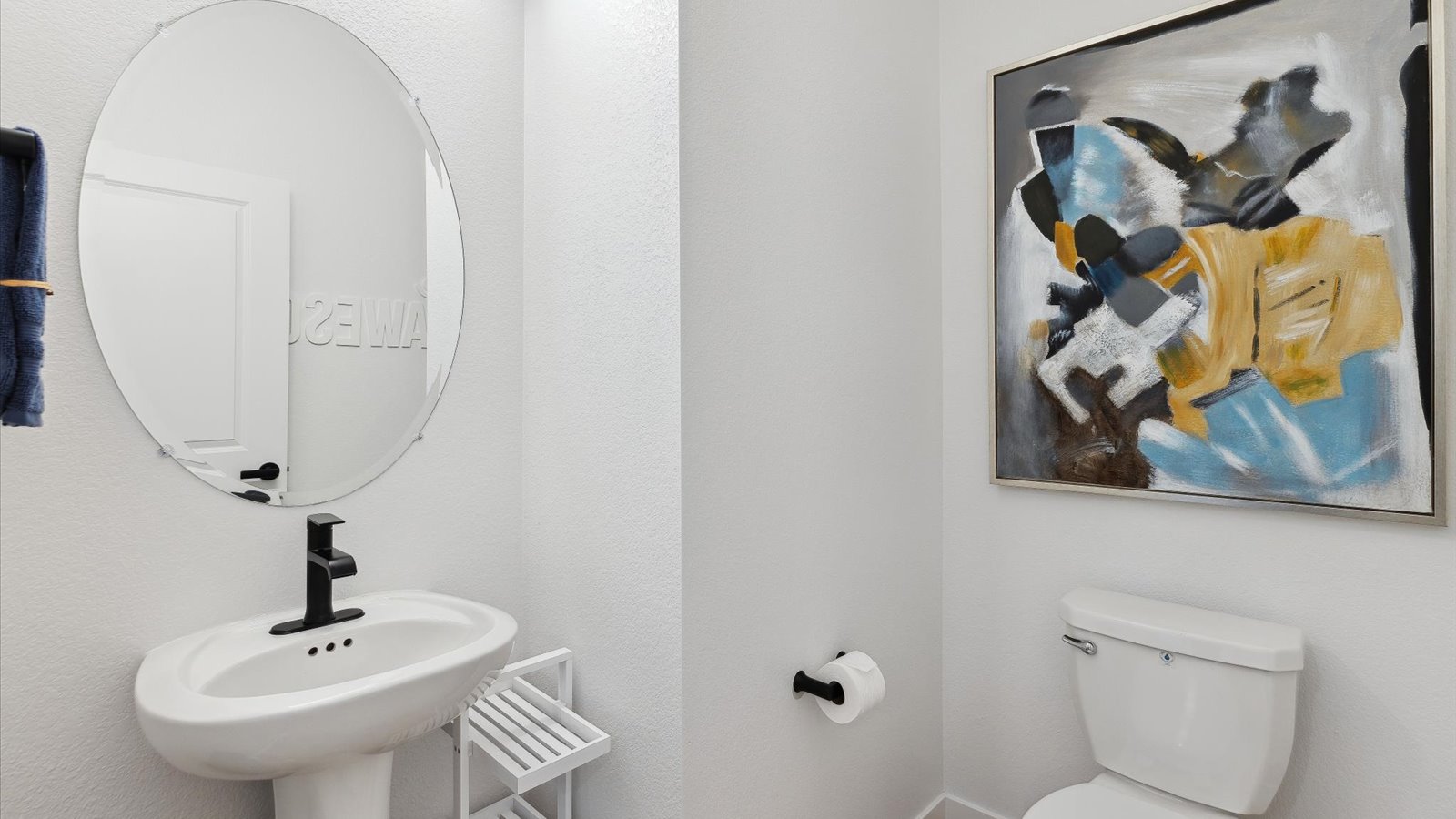 Larimer model home powder room features a pedestal sink with bronze faucet, oval mirror and LED lighting