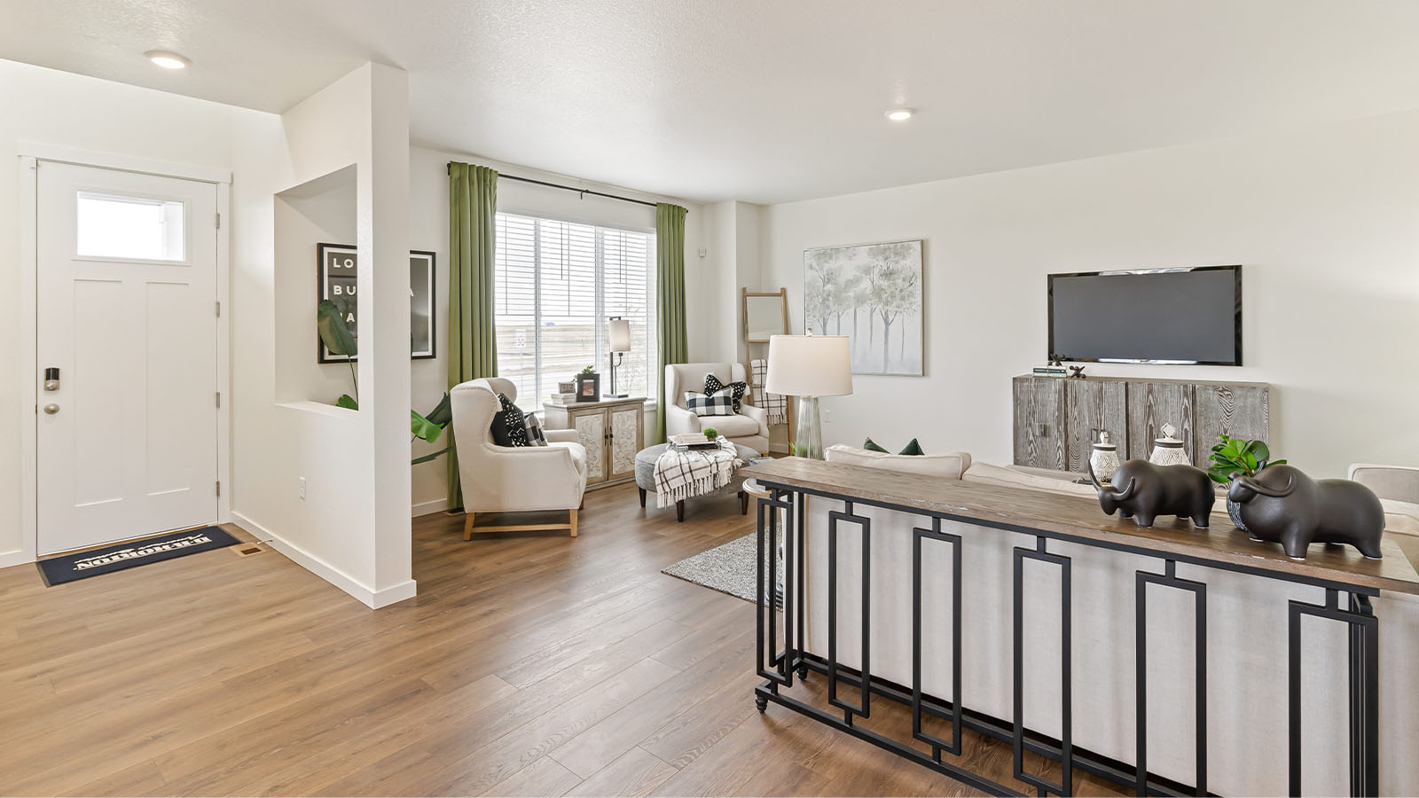 Alamosa floor plan great room and foyer showcasing paneled front door with window and expansive laminate hardwood flooring