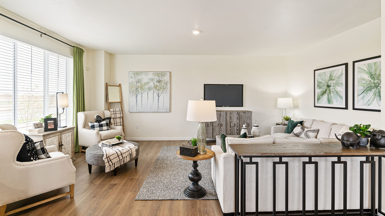 Alamosa home design great room displaying multiple large gridded windows and warm tone laminate hardwood flooring