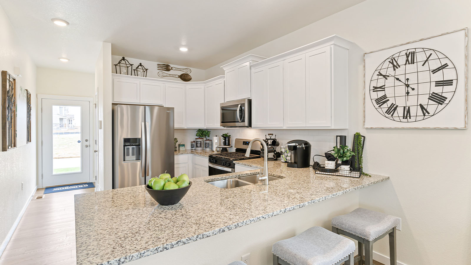Angled view of Alamosa kitchen with large peninsula seating area, undermount sink, stainless steel appliances and exit door