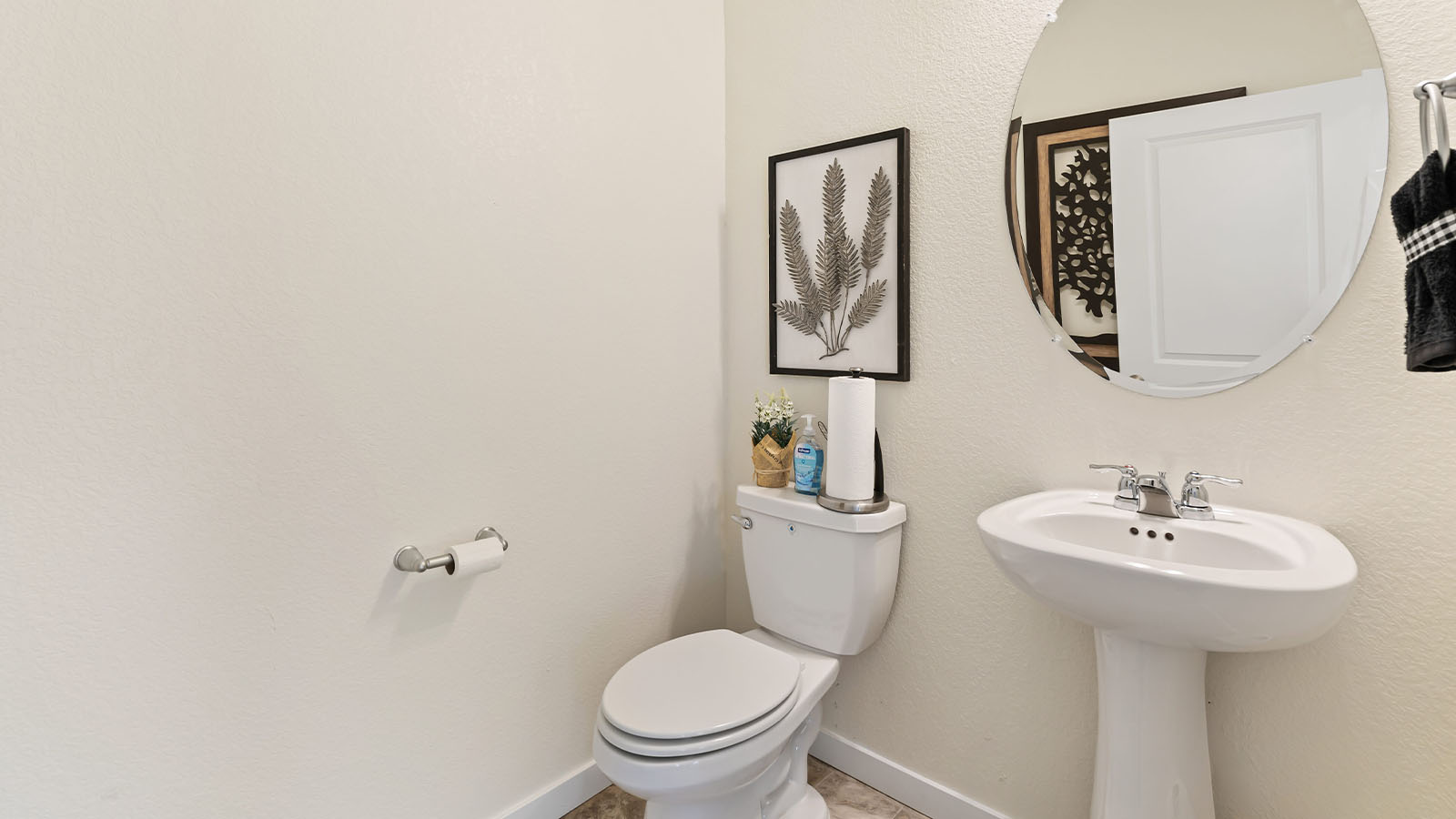 Main floor powder room in Horizon Uptown model home with white pedestal sink, chrome fixture and elegant oval mirror