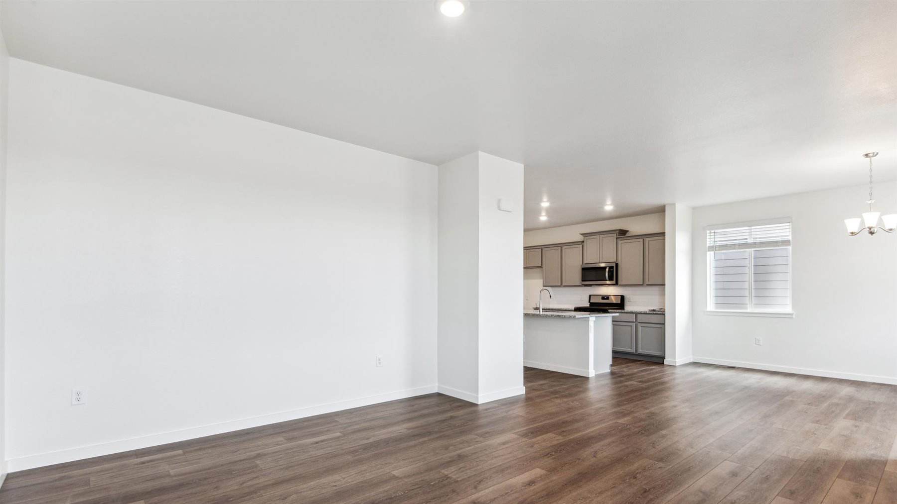 Alternate view of Elbert expansive great room wall and laminate hardwood flooring toward kitchen and dining in background