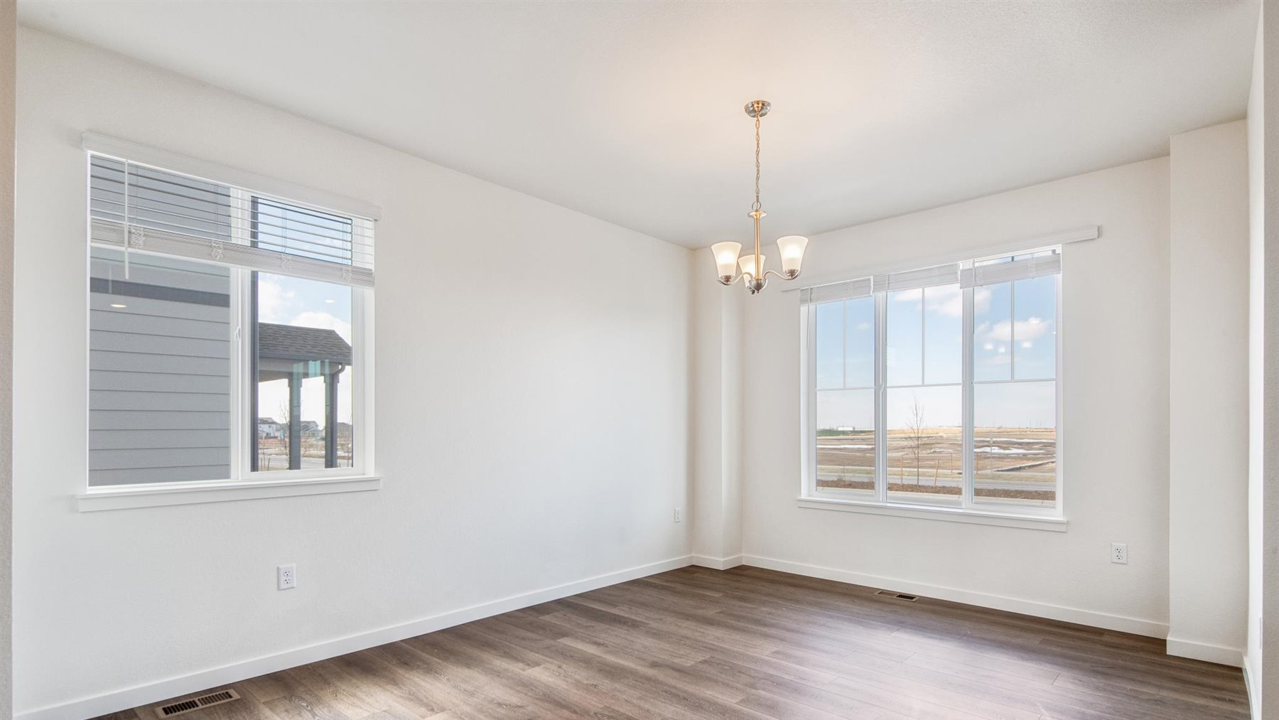 Close up view of Elbert plan dining room with brushed nickel chandelier, multiple operational windows with decorative grids