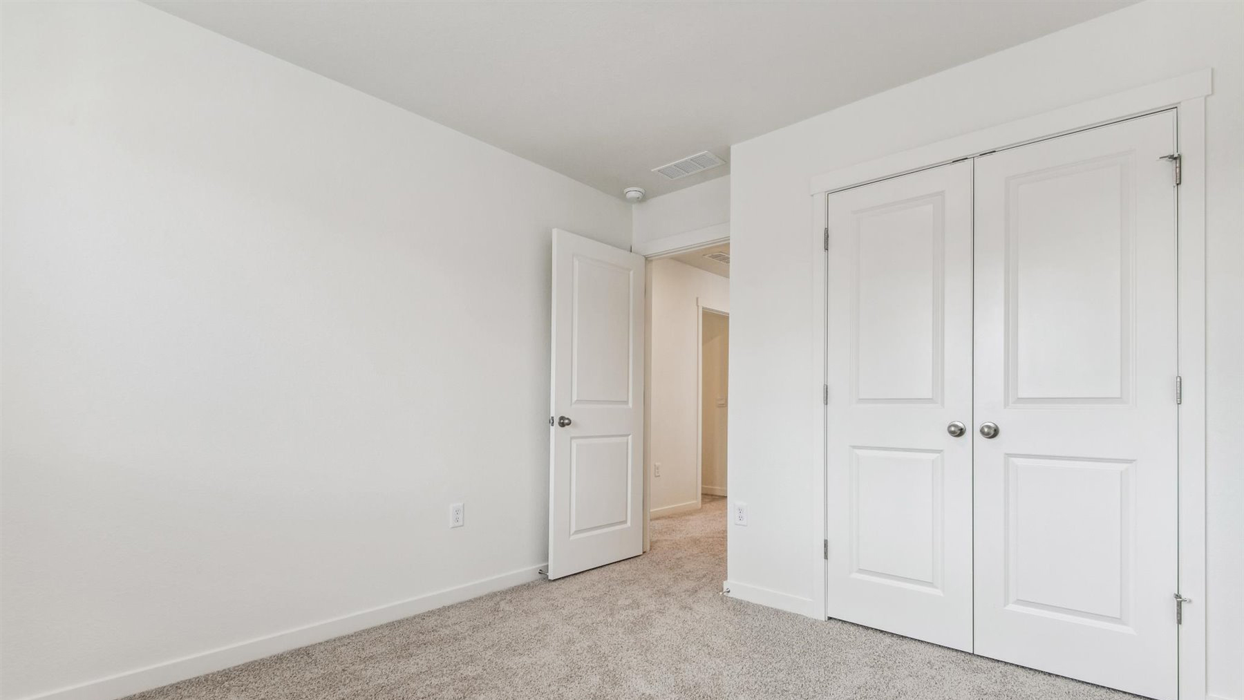 Rotated view of secondary bedroom #2 of Elbert floor plan showing entry door and multiple paneled double-door storage closet
