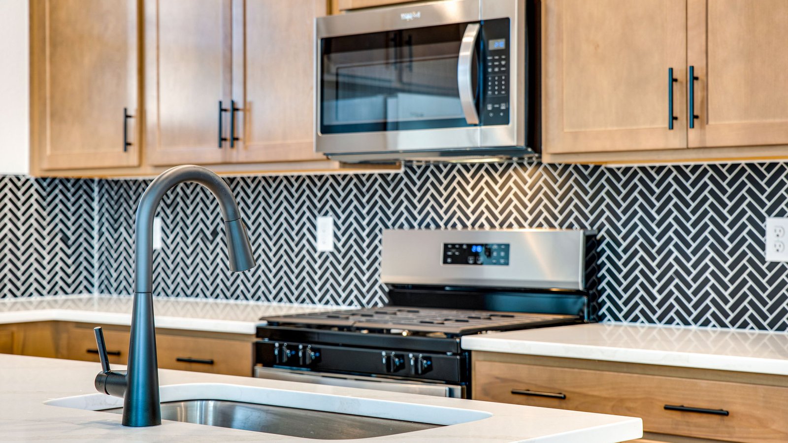 Modern kitchen in Muirfield floor plan featuring rich brown cabinetry paired with sleek black hardware and fixtures.