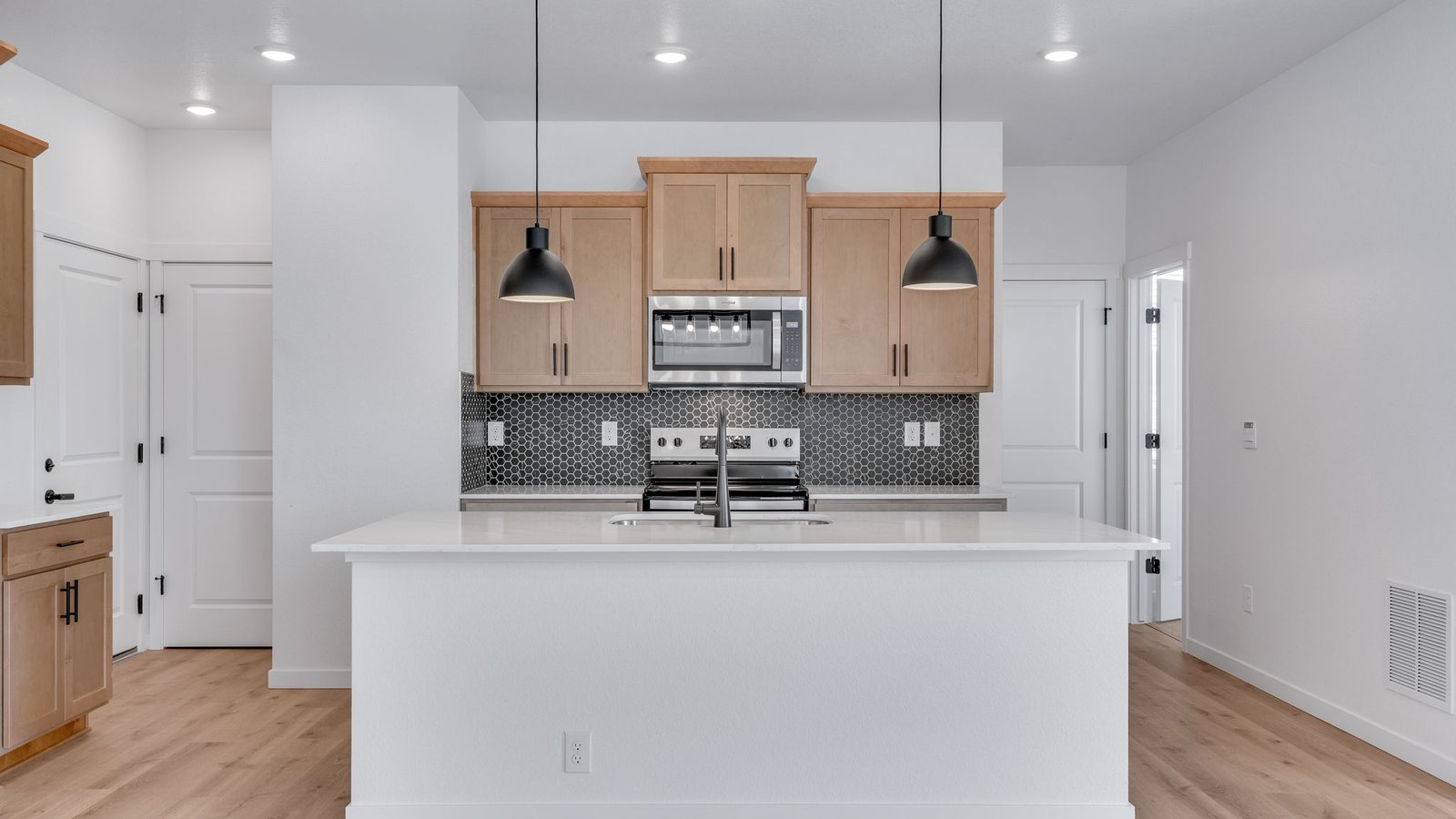 Modern kitchen in the Elm floor plan featuring stainless steel appliances, abundant cabinetry, and a large center island.