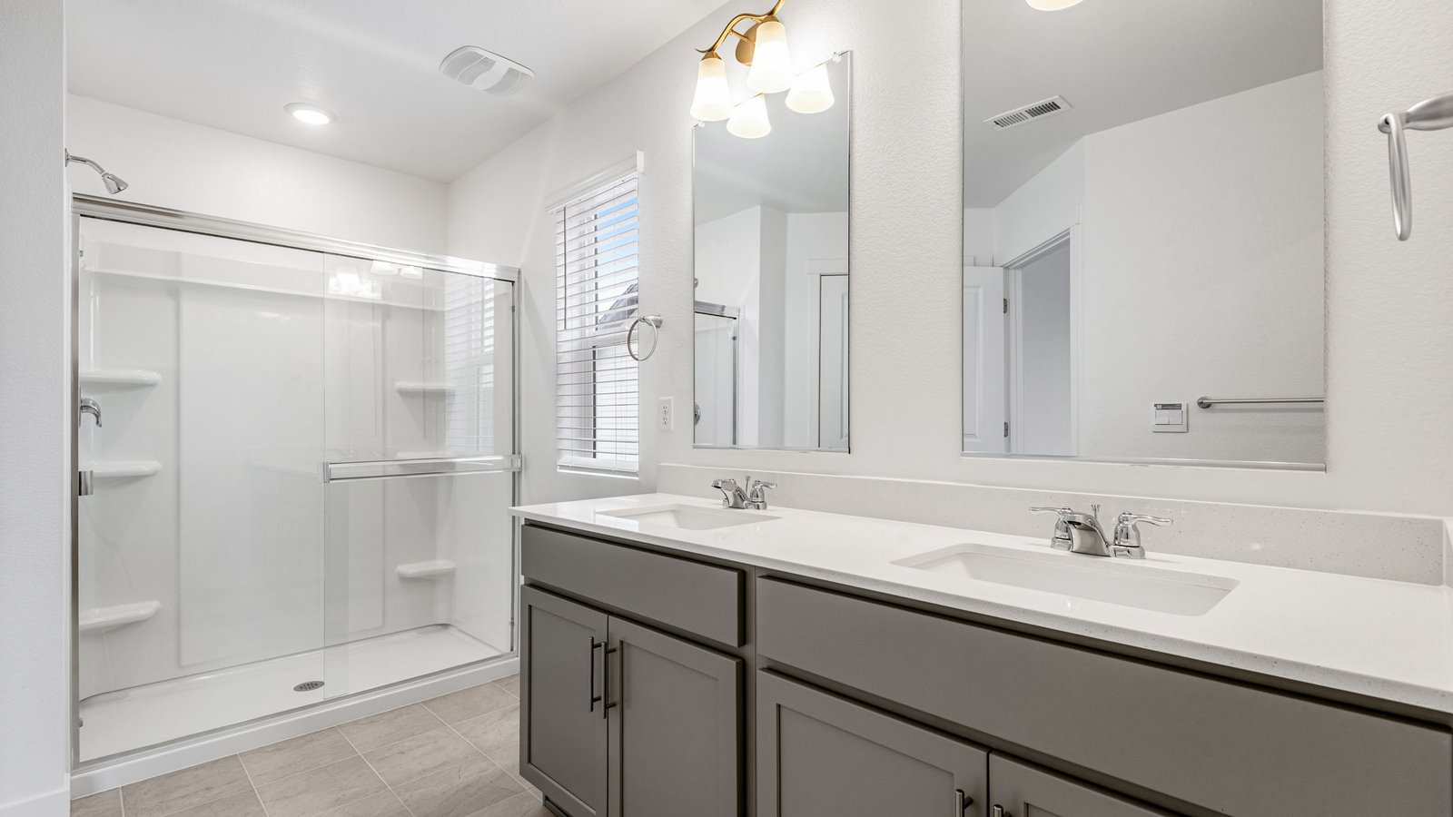Attached private primary bathroom with dual vanity sinks in new home in Lochbuie Colorado