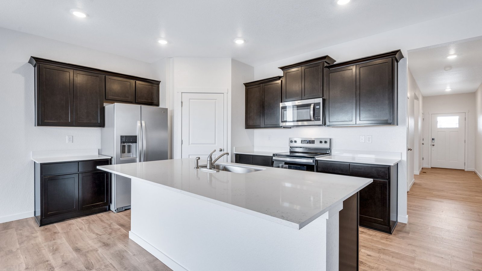 Modern kitchen in the Chatham floor plan at Fossil Creek Ranch featuring a large island, stainless steel appliances, and walk-in pantry.