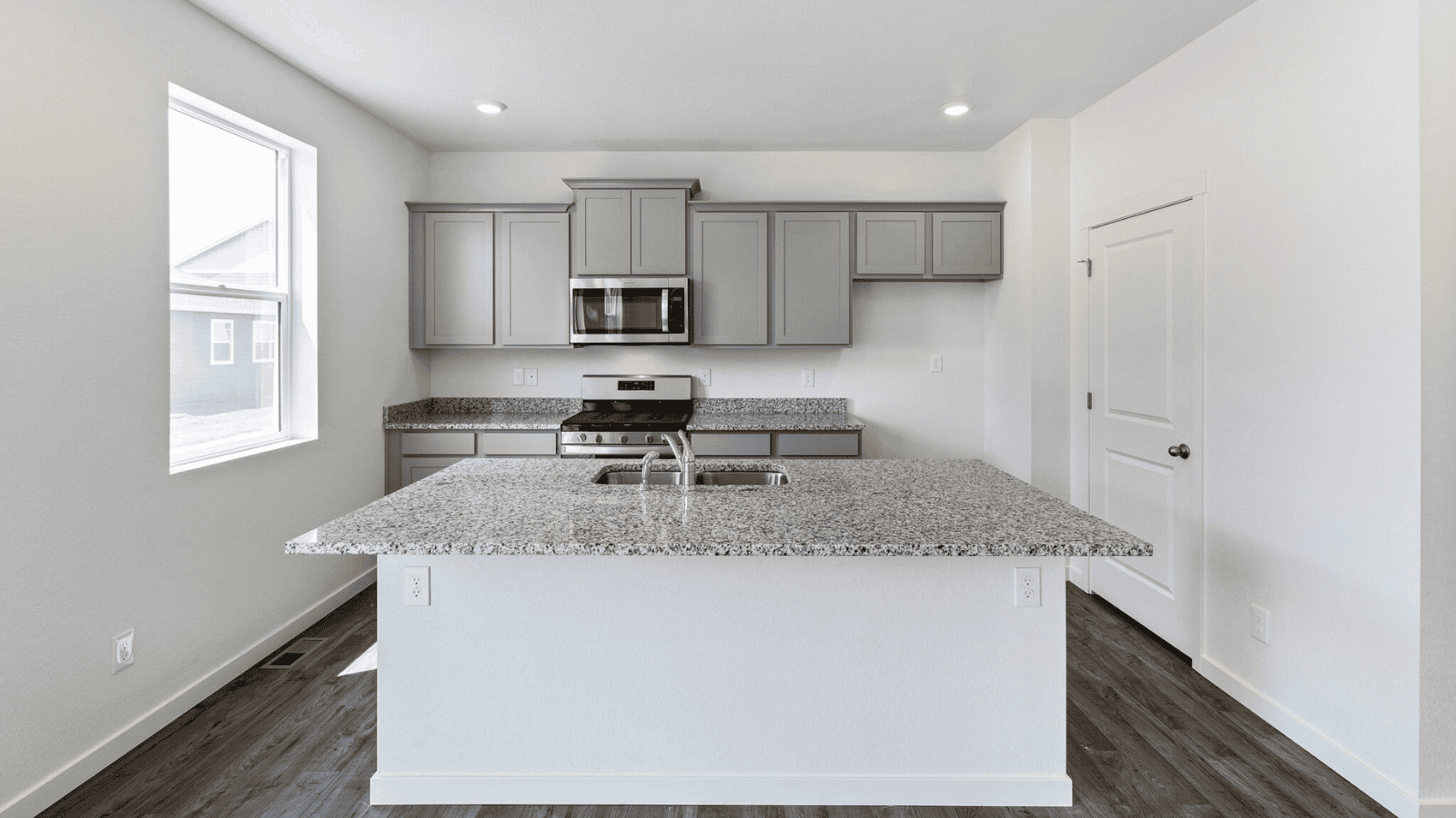 Modern Sienna kitchen featuring stainless steel appliances, white cabinetry, a pantry, and a large center island.