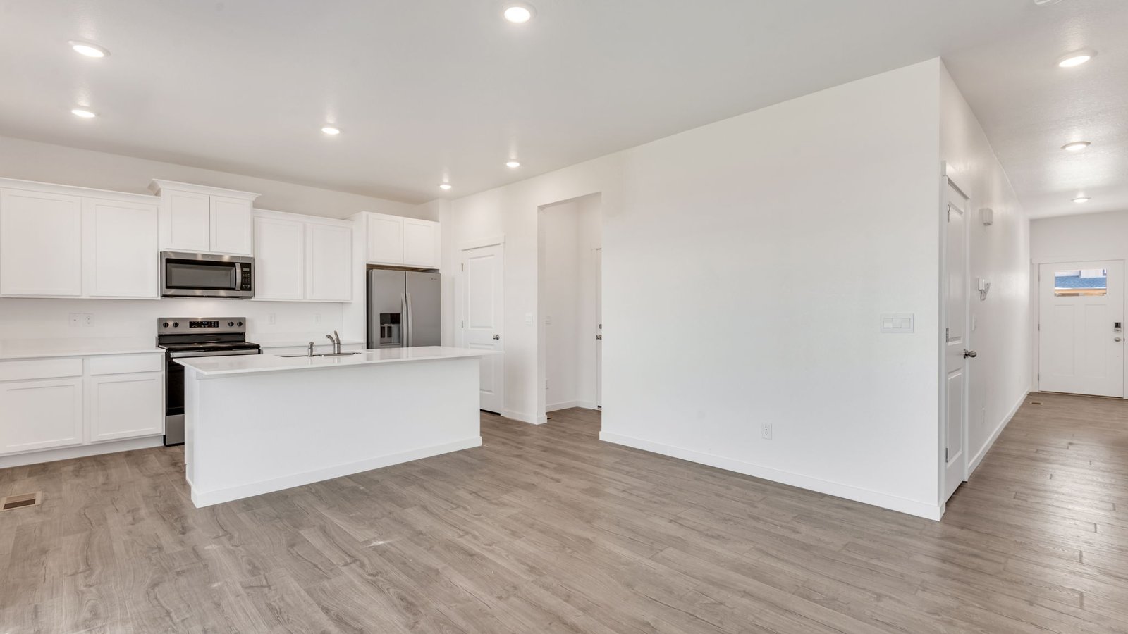 Bellamy home kitchen with large center island, cabinetry, stainless steel appliances, and open layout.