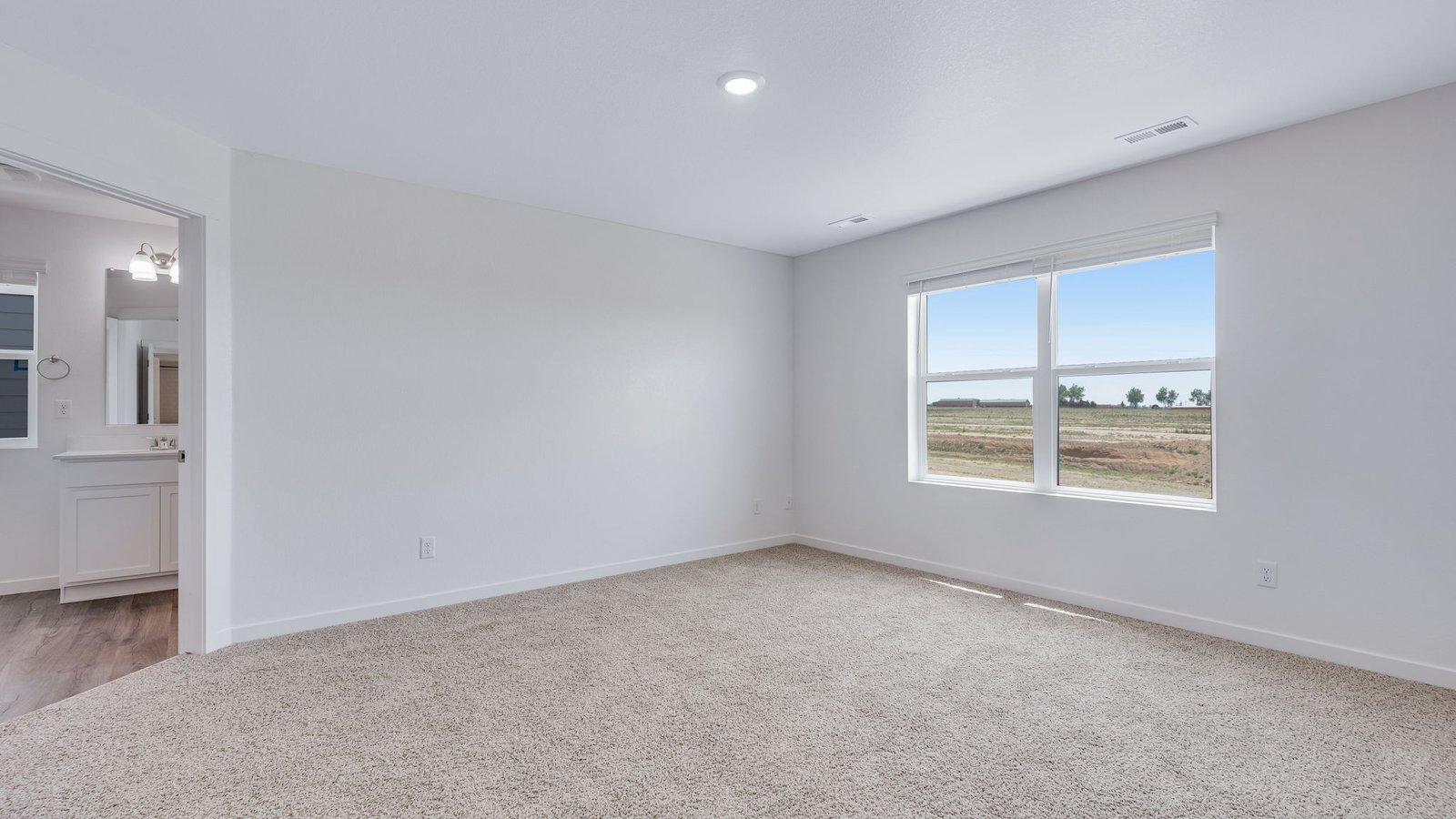 Spacious primary bedroom with large windows in new home community Vista Meadows