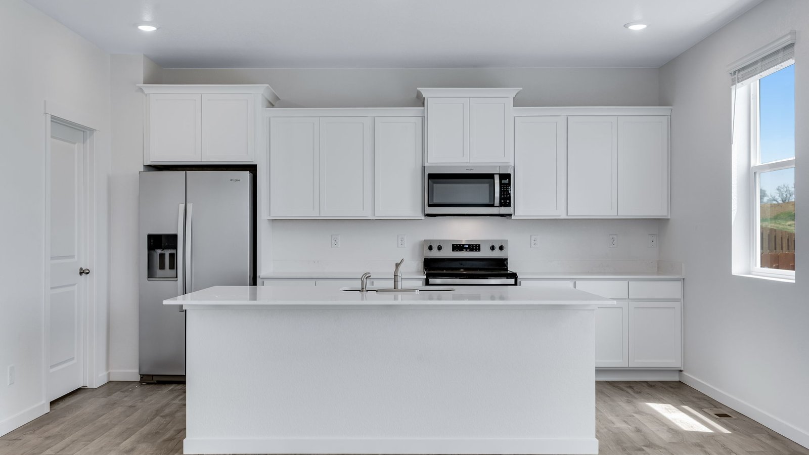 Bright kitchen featuring white cabinetry, sleek quartz counters, and stainless steel appliances
