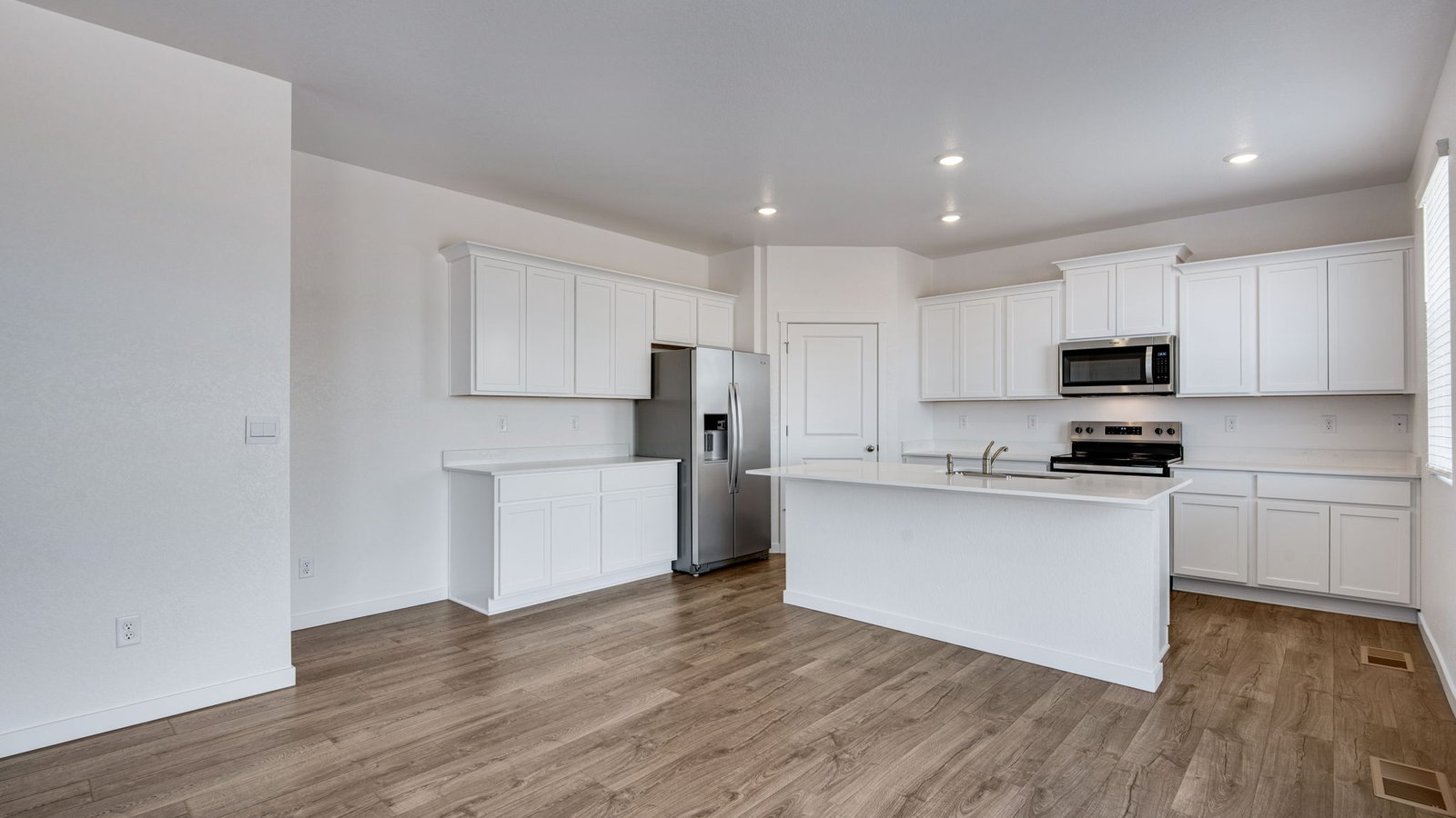 kitchen with large island and lvp flooring in new construction home by d.r. horton