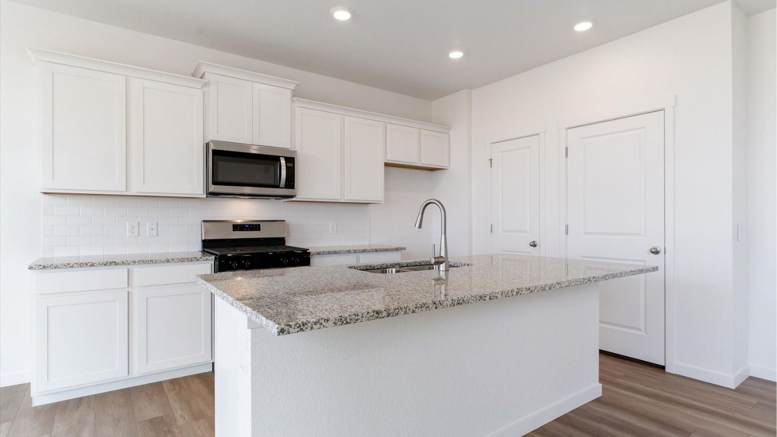 Open‑concept kitchen with granite countertops, gas range, and modern cabinetry in the Cabral floorplan at The Ridge at Johnstown.