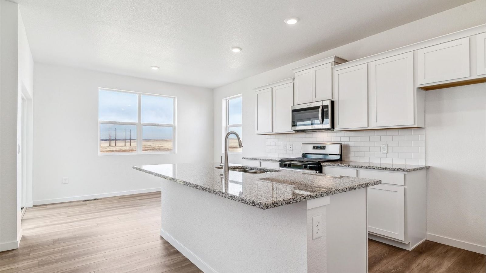 Kitchen featuring granite countertops and gas stove, open to dining and living areas in a Johnstown, Colorado home.
