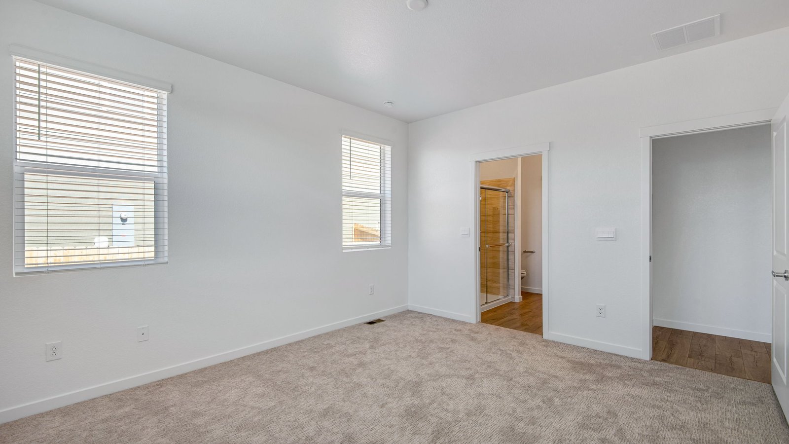 Spacious primary bedroom in the Harmony floor plan featuring large windows, comfortable living space, and a private location at the rear of the home.
