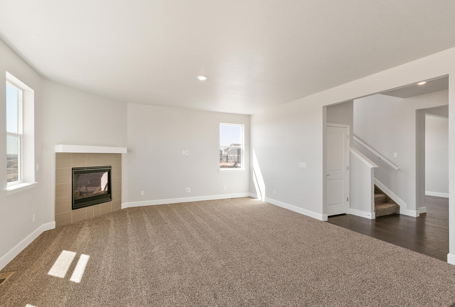 open space living room and kitchen with four windows, fireplace, and carpet floor