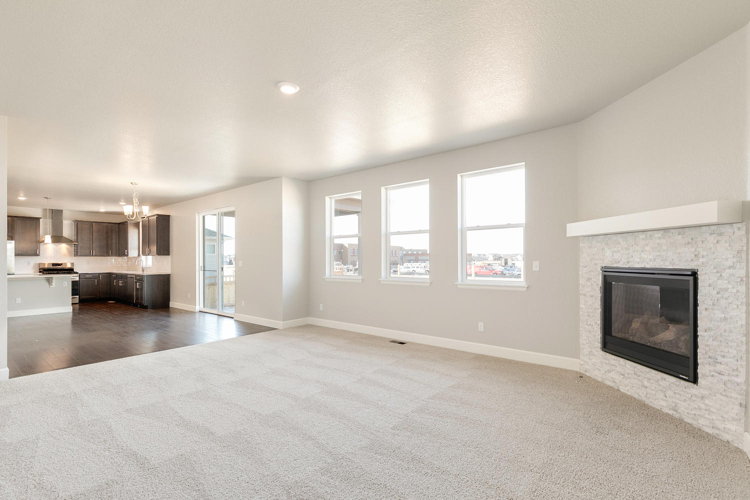 living room with a fireplace, three windows, a back door, and carpet floor