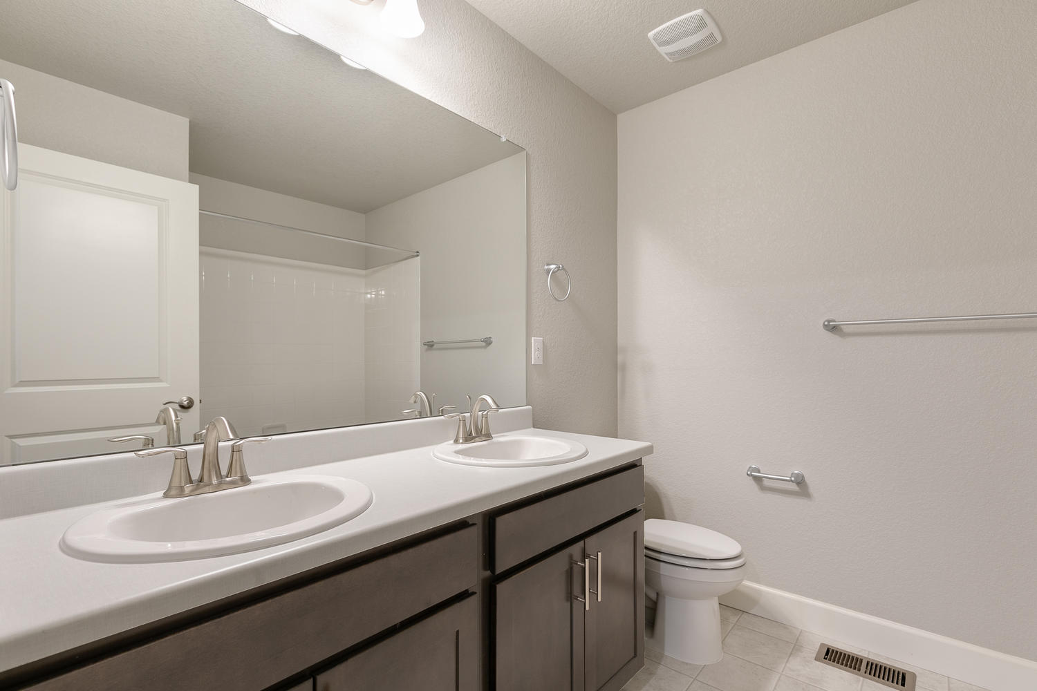 brown cabinet bathroom with dual-basin sink and a toilet