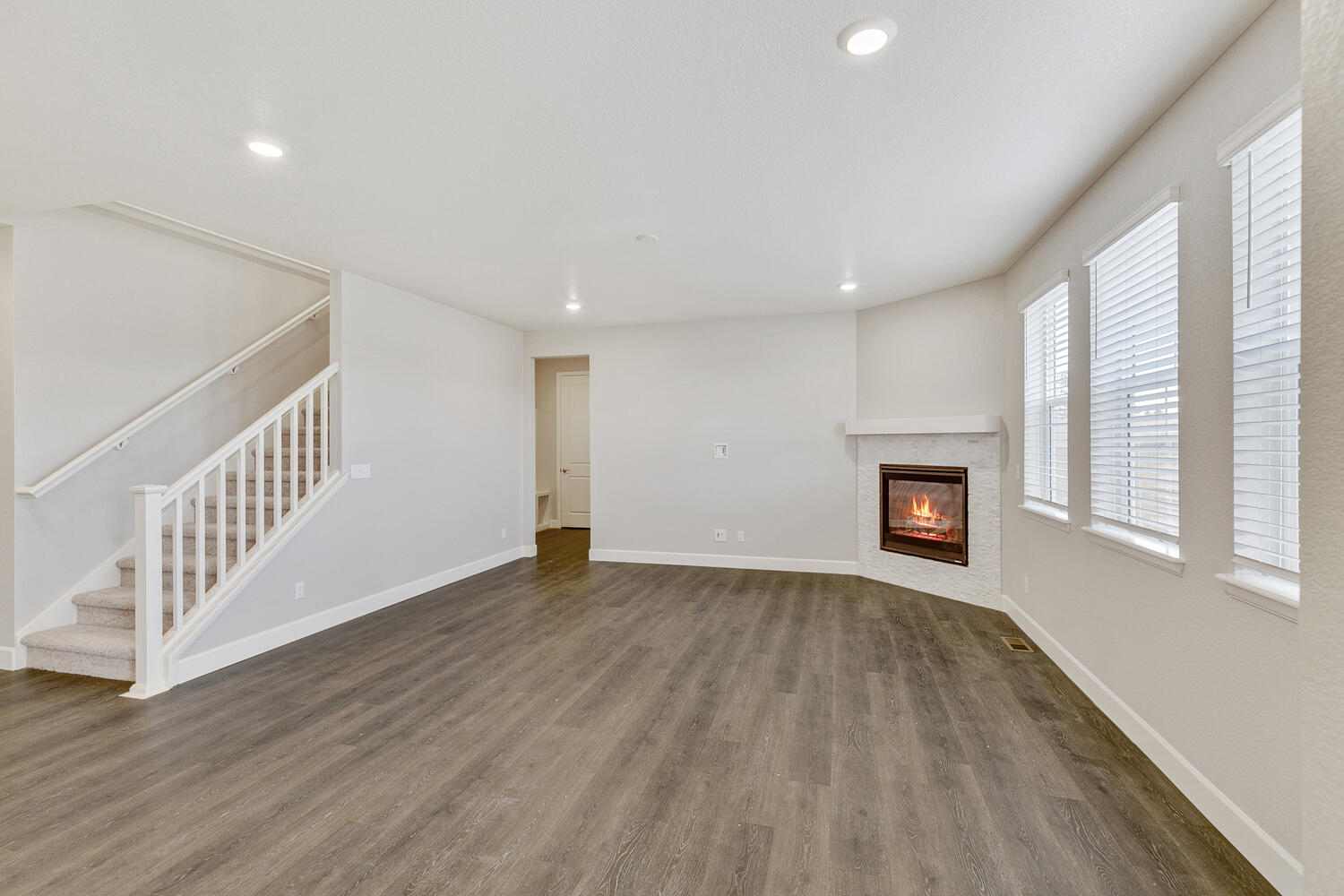 open space concept living room with a fireplace, stairs and three windows