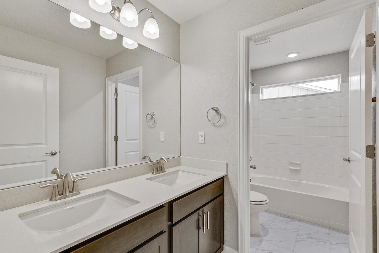 brown cabinet bathroom with dual-basin sink and tub and toilet and a separate room