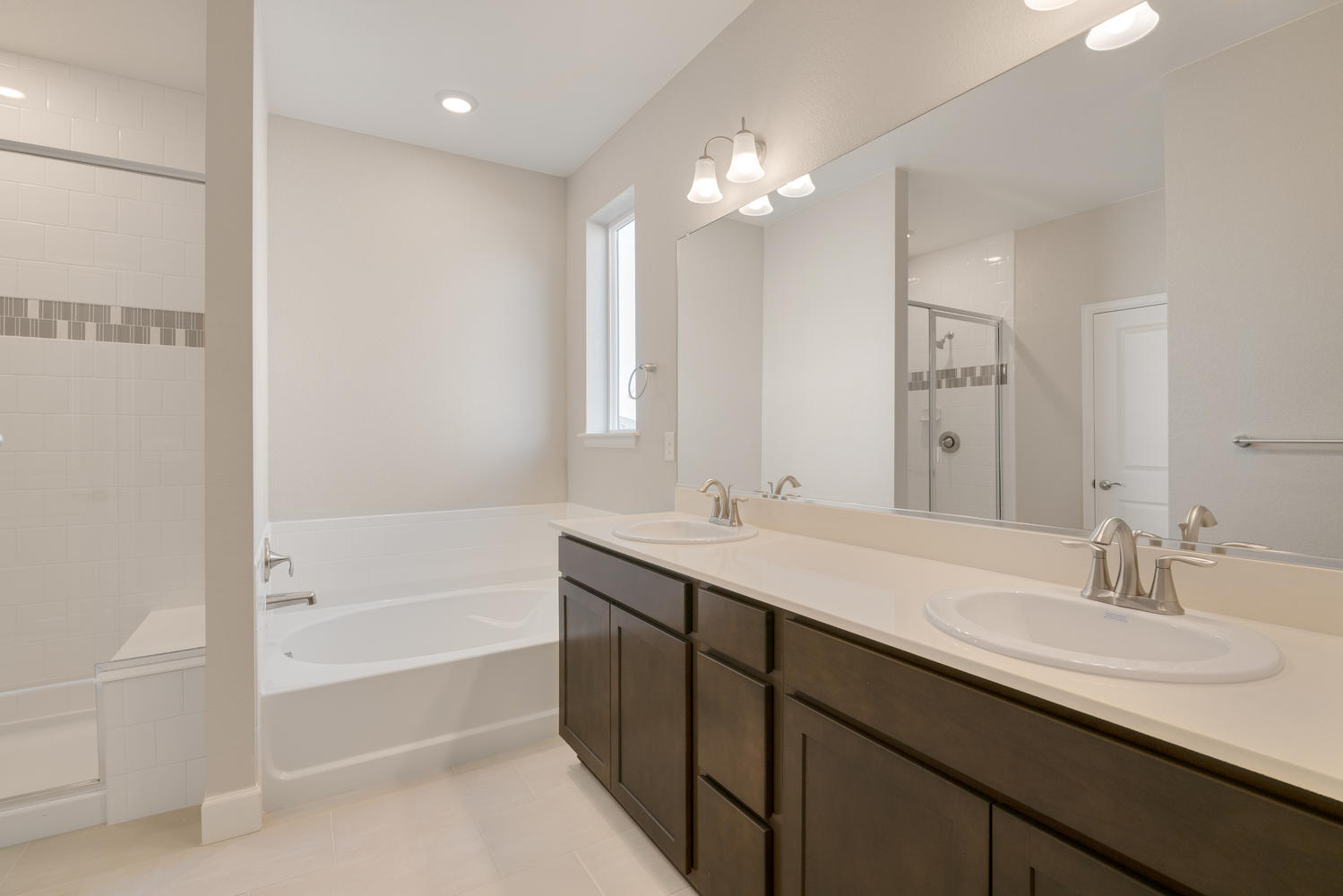 brown cabinet bathroom with dual-basin sink, shower and a tub