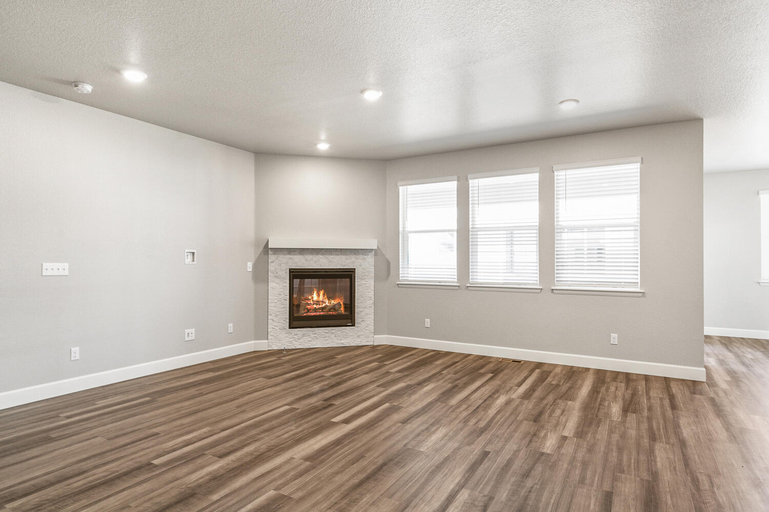 open space concept living room with three windows and a fireplace