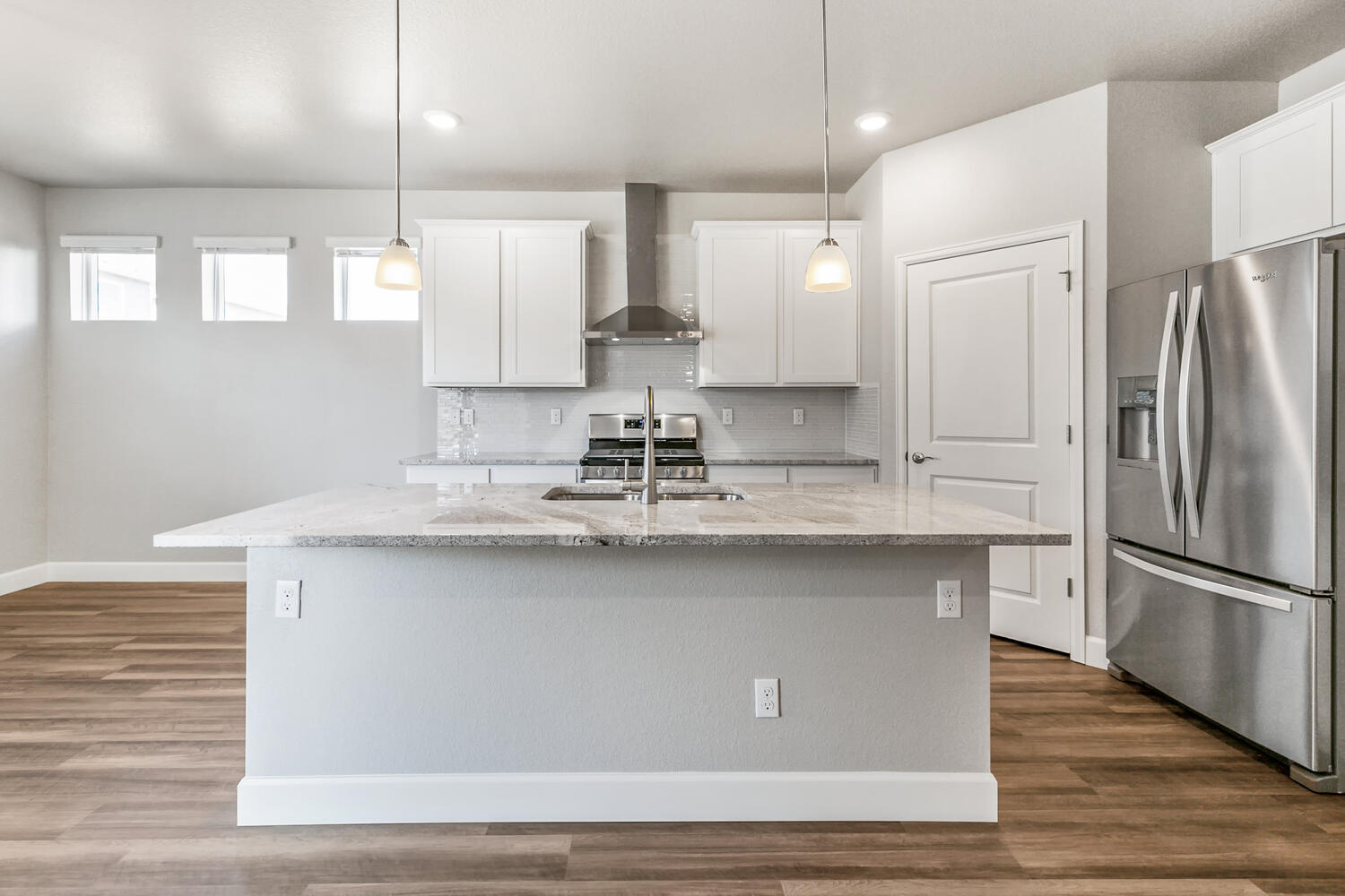 white cabinet kitchen with stainless steel appliances, windows and an island