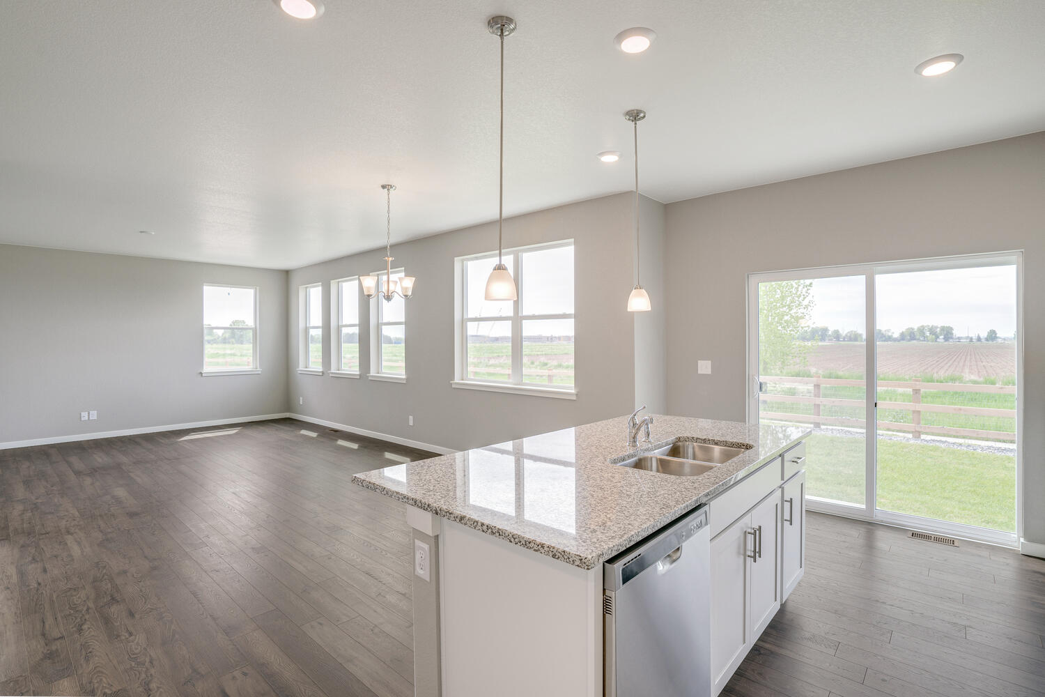 kitchen view of open space living room with three windows and a back door