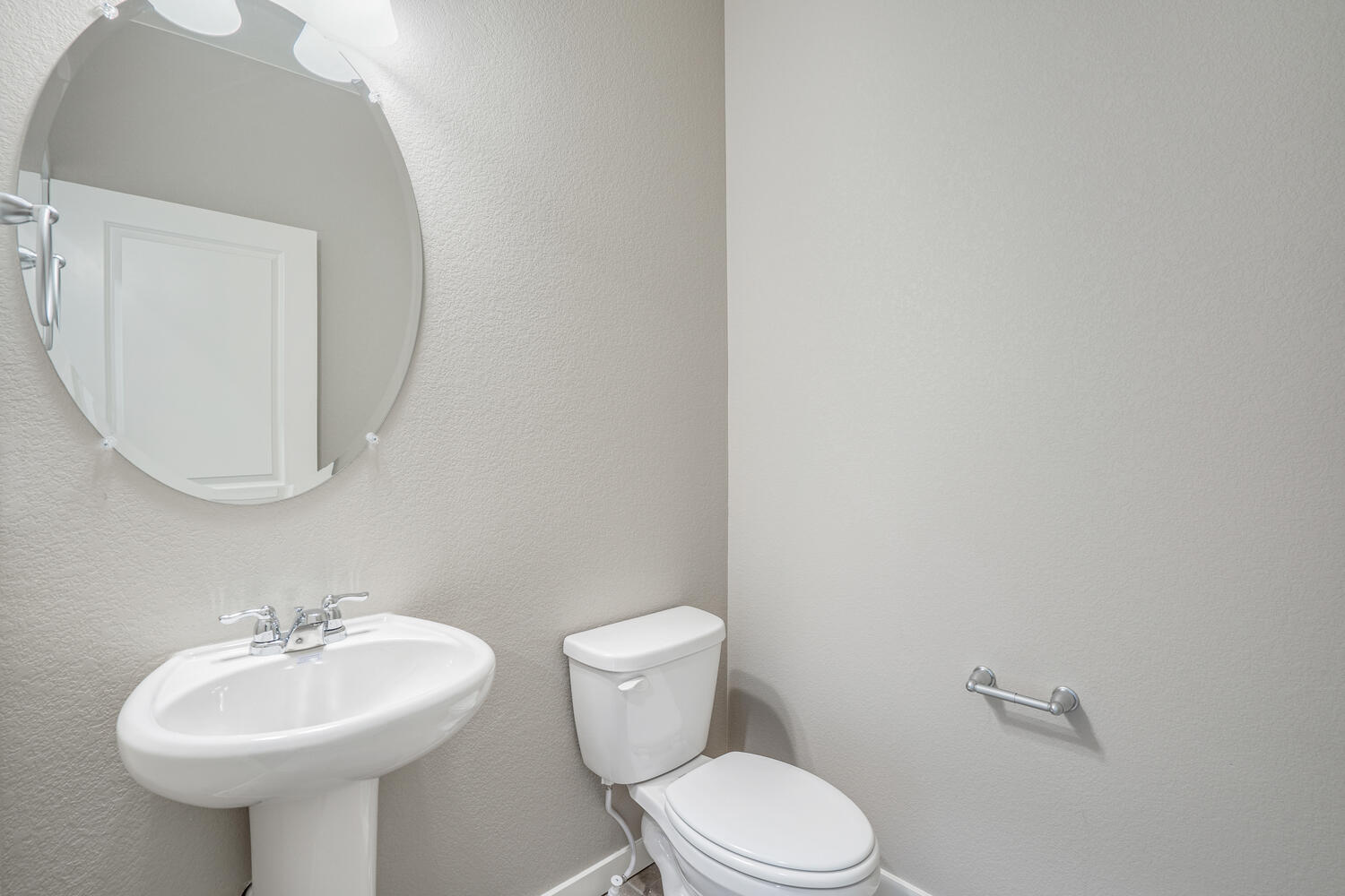 half bath with a round mirrow,  a toilet and a sink