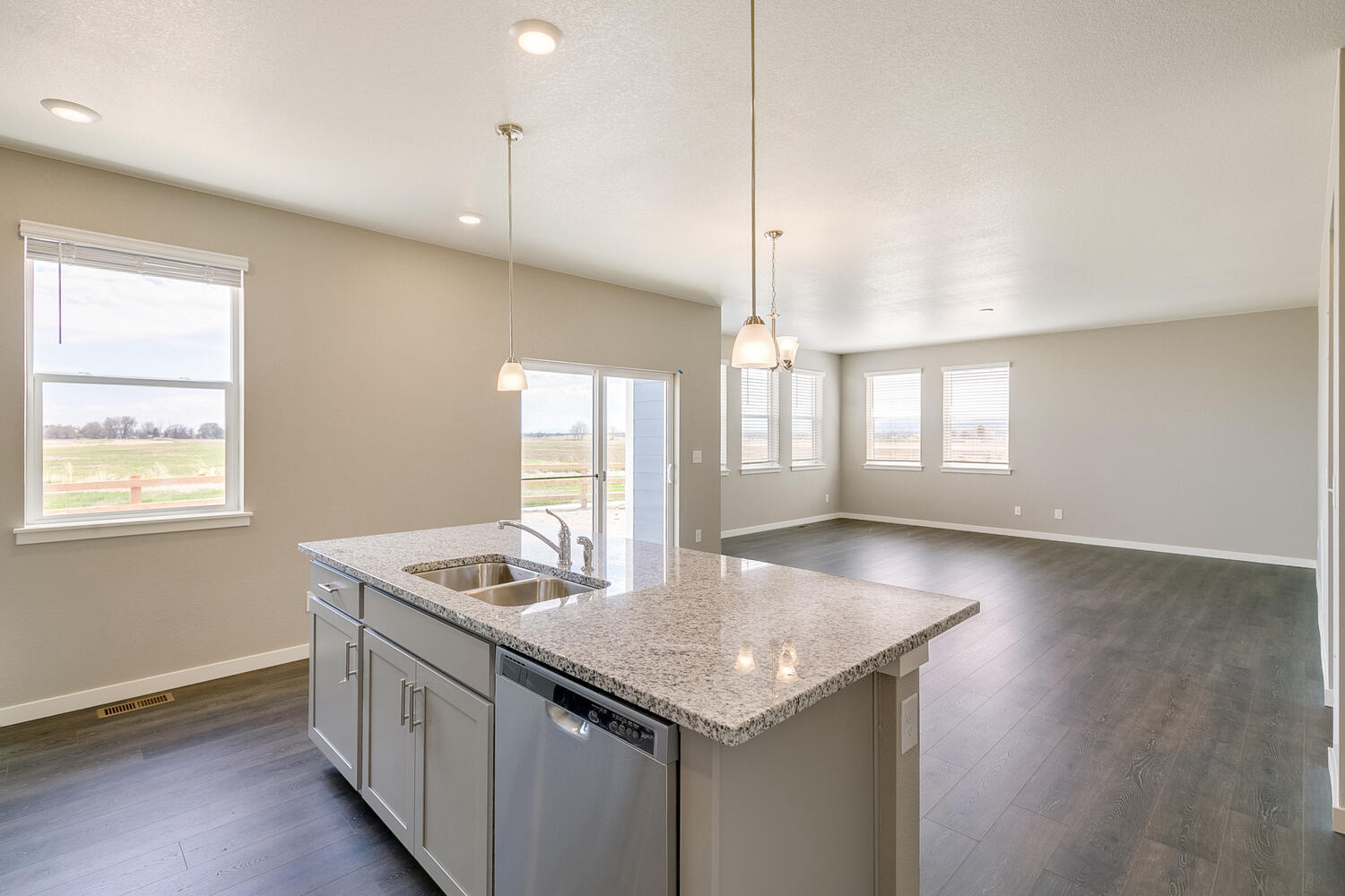 kitchen view of open space living room with three windows and a back door