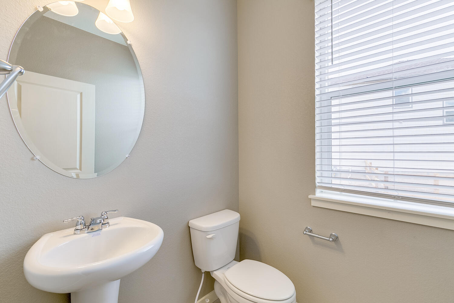 half bath with a round mirrow,  a toilet and a sink