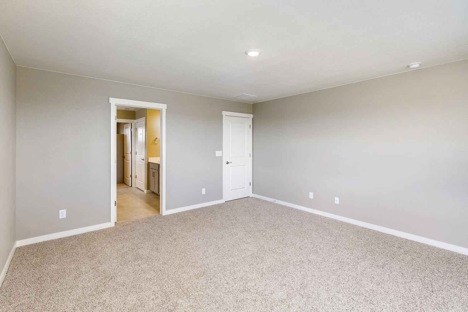 bedroom with carpet floor and door to bathroom