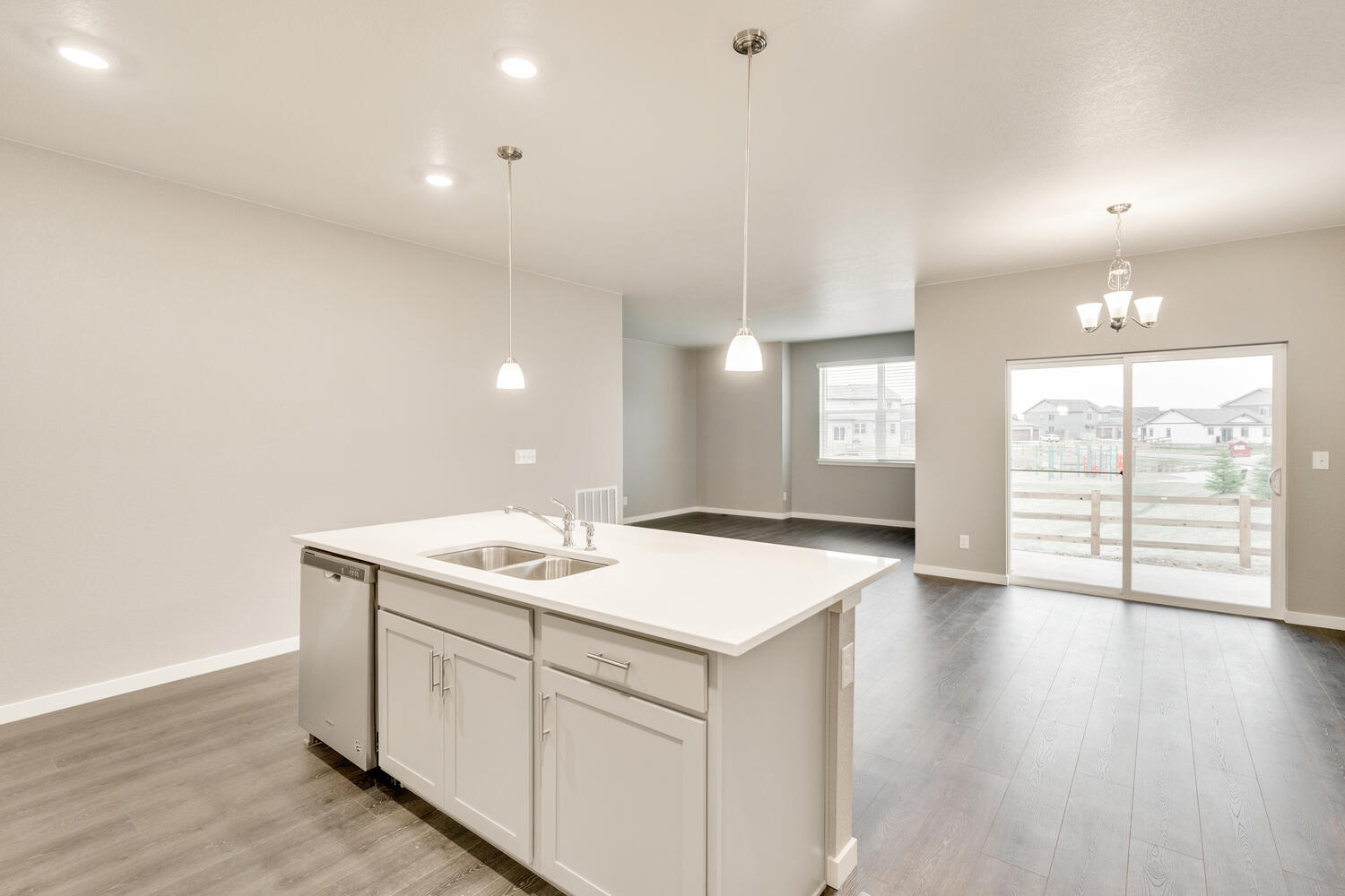 kitchen view of open space living room with three windows and a back door