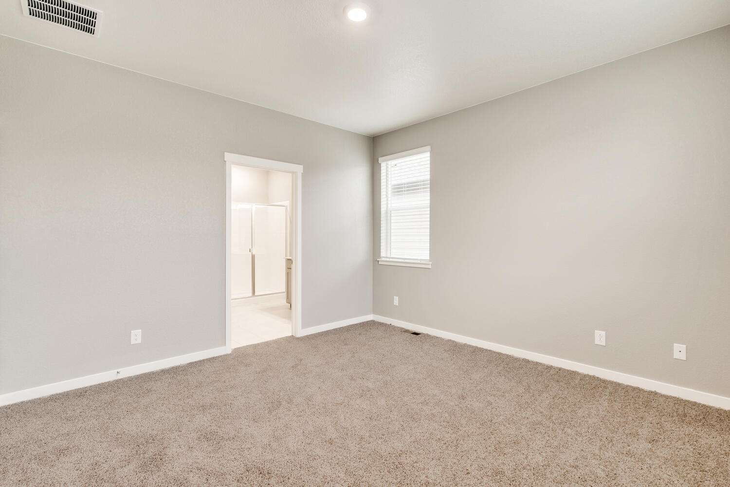 bedroom with a window, carpet and door to bathroom