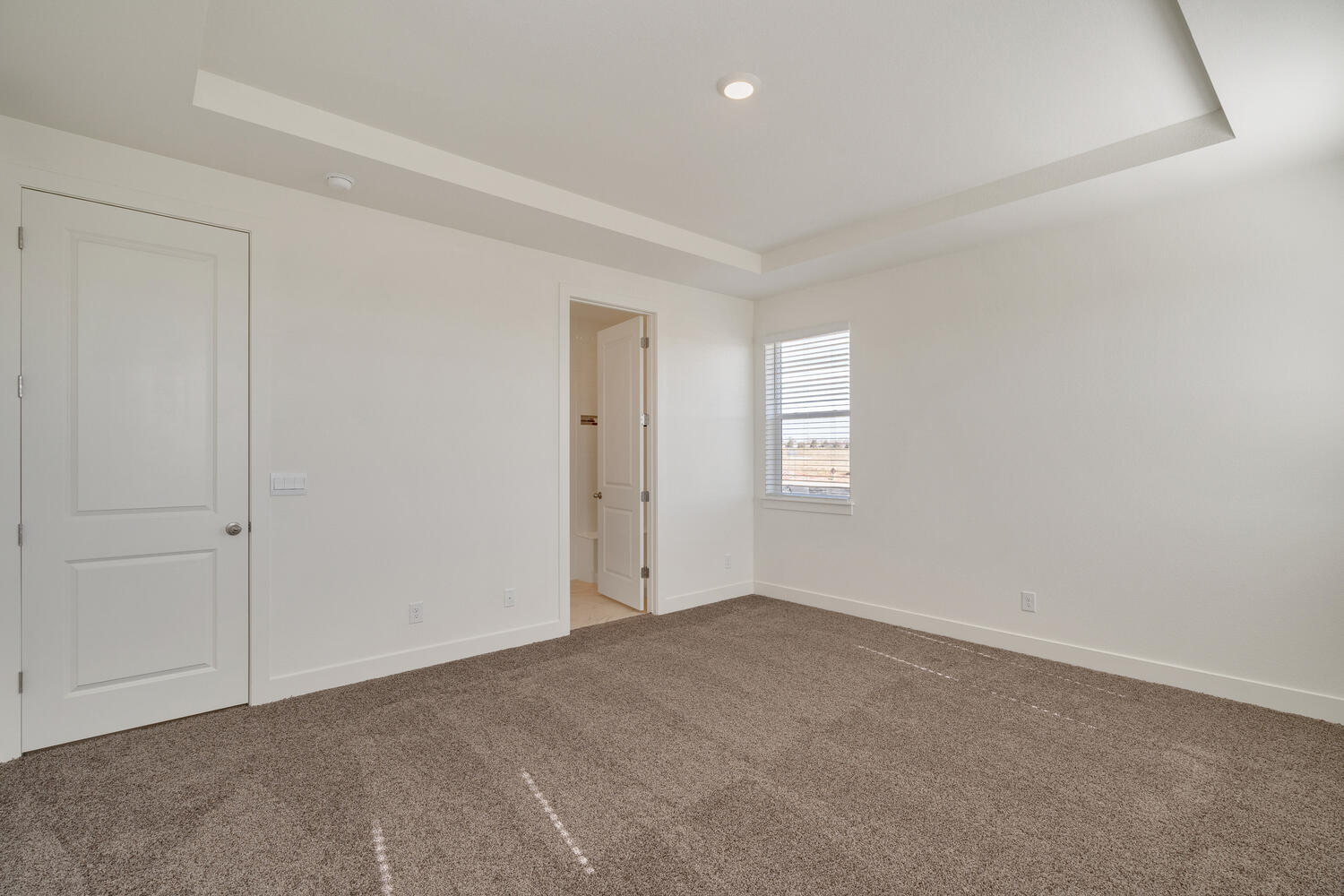 bedroom with crown molding, carpet floor and door to bathroom