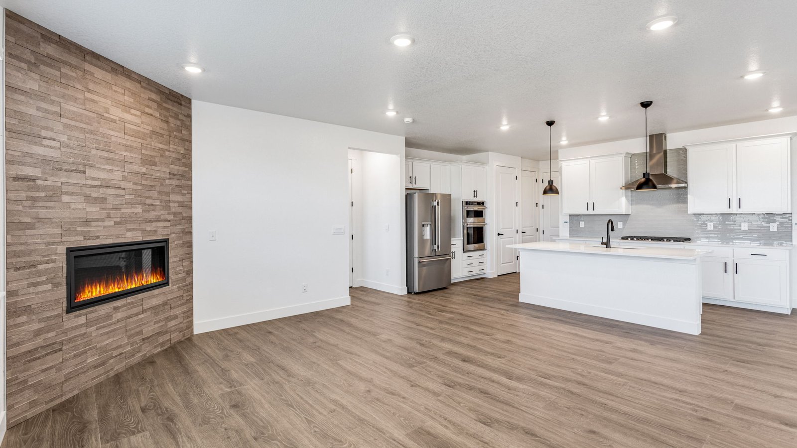Bright great room in the Grover floor plan with open-concept living space and durable laminate plank flooring.