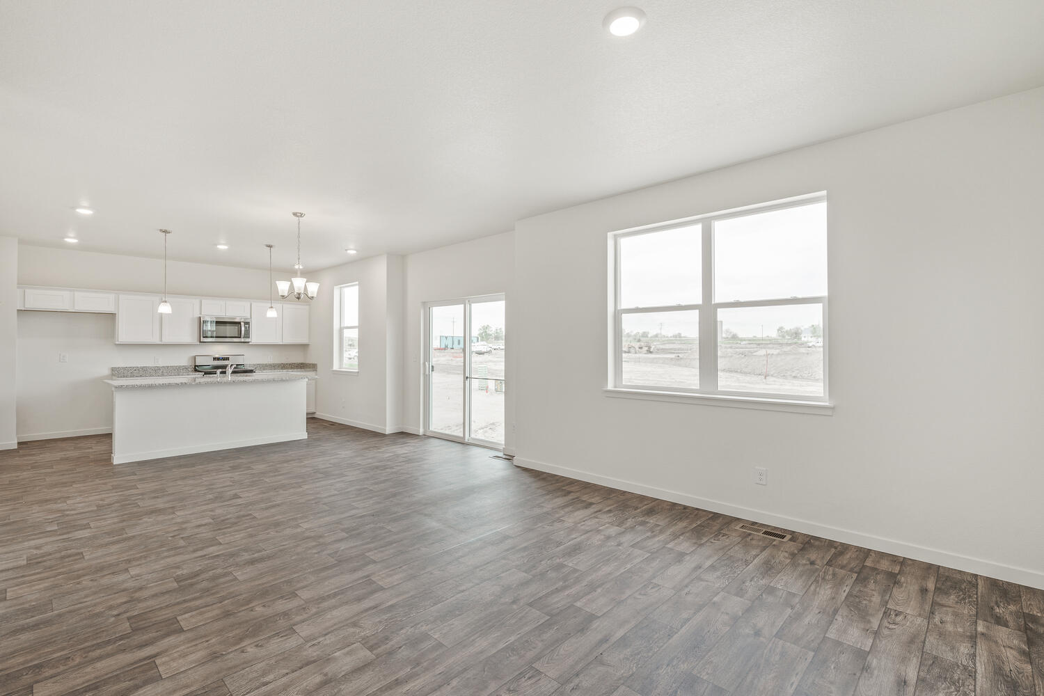 spacious living room and kitchen with two windows and a back door