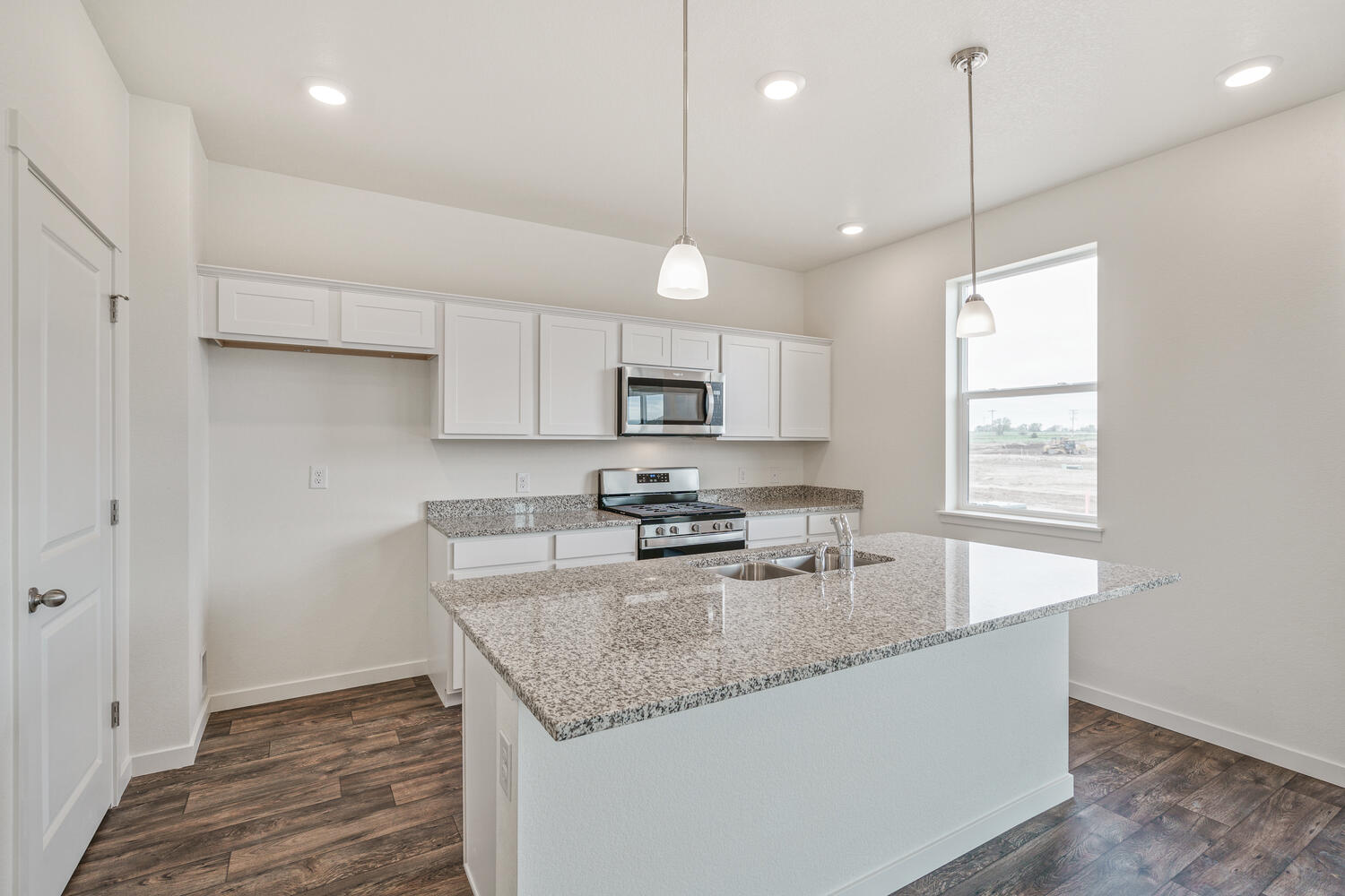 white cabinet kitchen with stainless steel appliances, an island, and a window