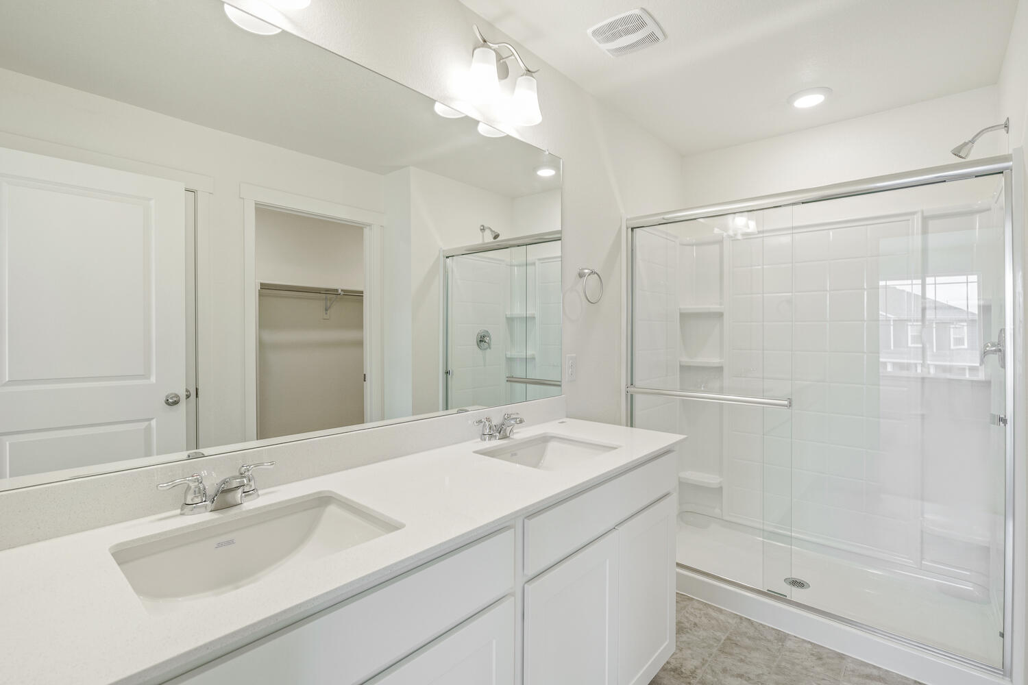 white cabinet bathroom wtih dual-basin sink and a shower