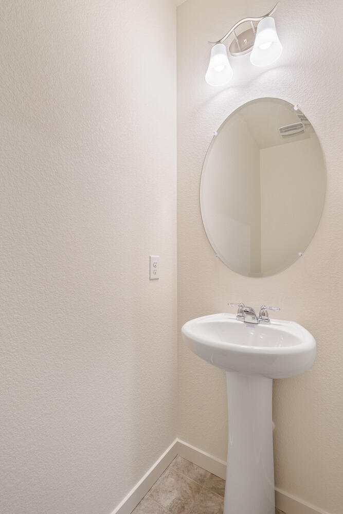 half bath with a sink and round mirrow