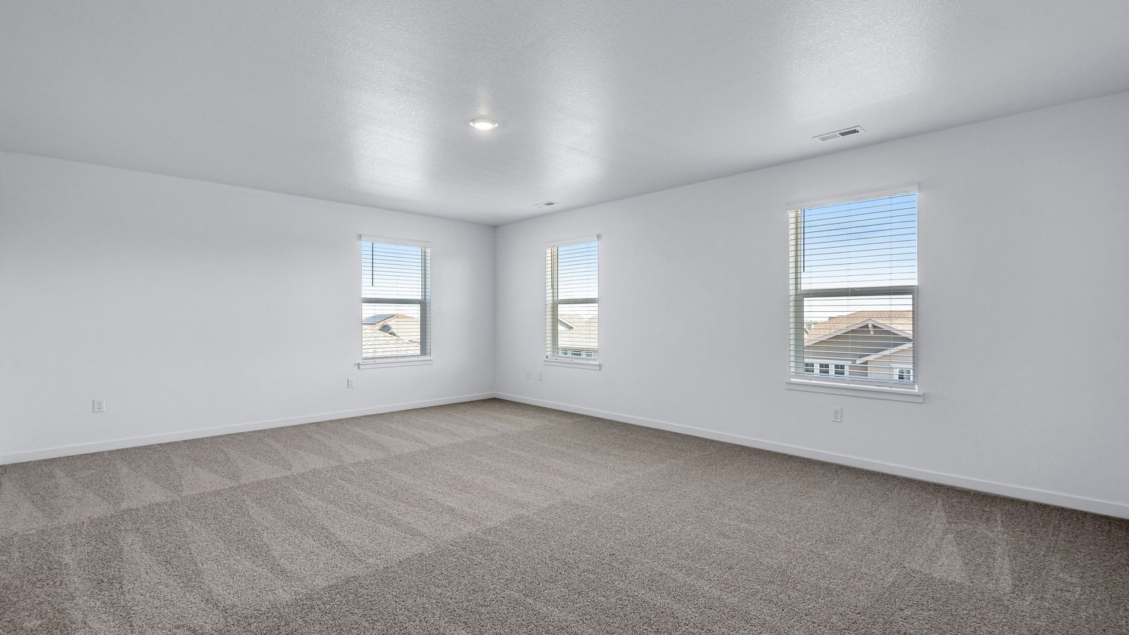Spacious primary bedroom with large windows in new home community Brighton Crossing