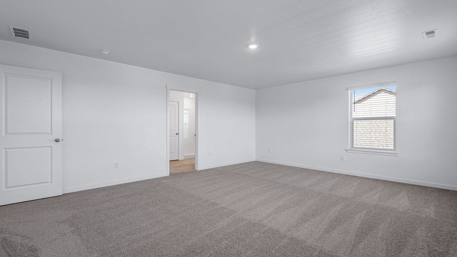 Spacious primary bedroom with large windows in new home community Brighton Crossing
