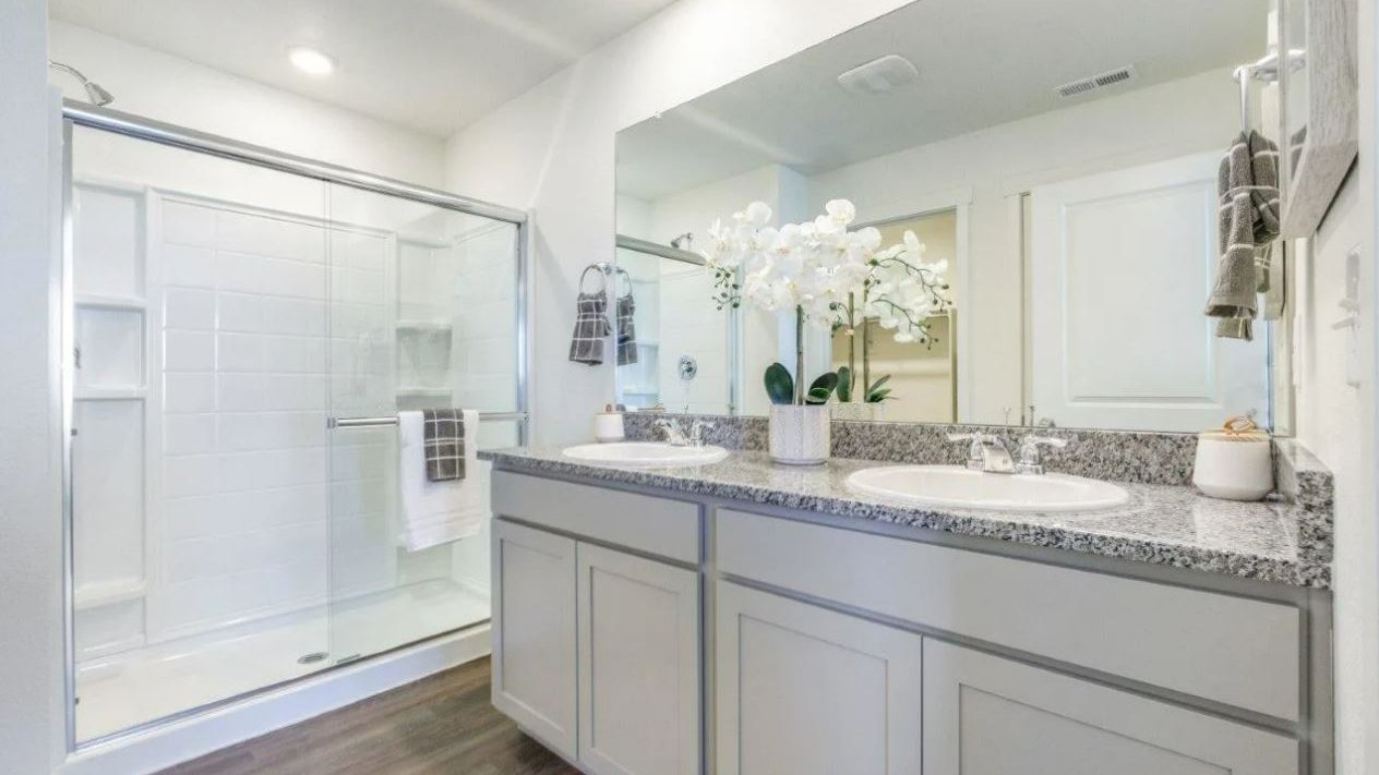 Private attached bathroom in new home with dual vanity sinks